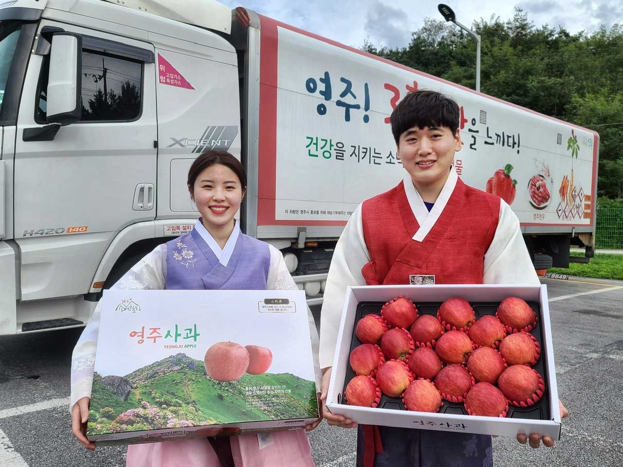 SK머티리얼즈 직원이 영주 특산물 광고가 게재되어 있는 물류 트레일러 앞에서 영주 사과를 들고 있는 모습 2